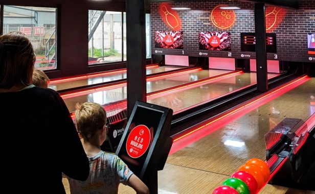 Boliche-pista-França-Games-Park-França Mulher adulta e criança estão lado a lado, jogando boliche em uma pista da Imply®