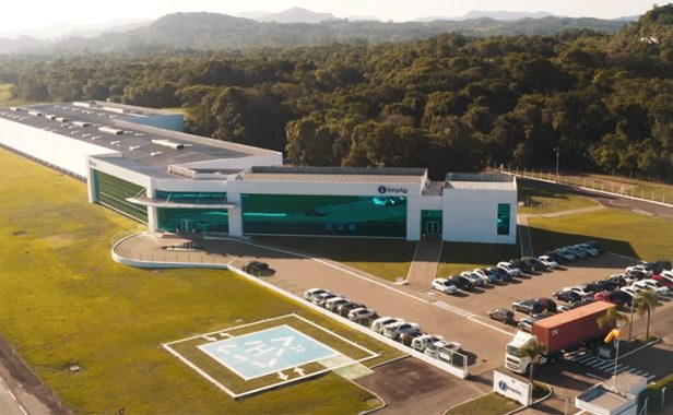 IMPLY Tecnologia Visão externa da sede da Imply em Santa Cruz do Sul. Mostra a fachada e toda sua ampla estrutura, incluindo o lado ao fundo e o bosque ao redor que faz parte da empresa.