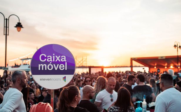 Pessoas em evento ao ar livre com caixa móvel ao fundo.