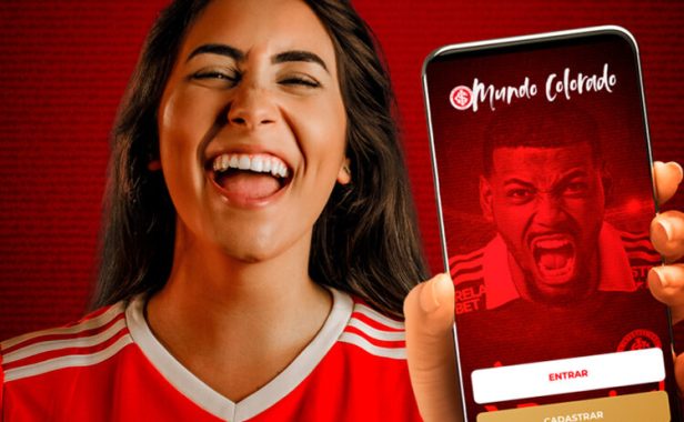 Mulher sorrindo, segurando e mostrando um celular com o aplicativo do Mundo Colorado.
