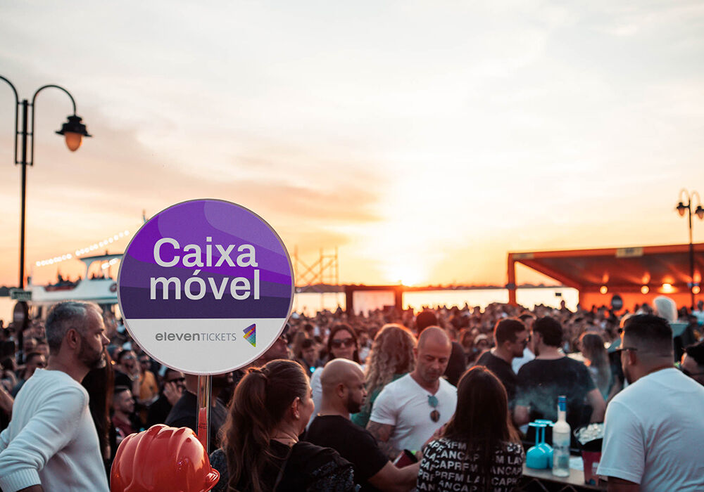 Pessoas em evento ao ar livre com caixa móvel ao fundo.