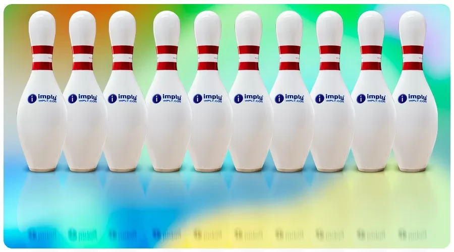 Fila de pinos de boliche/bowling brancos com faixa vermelha e logo “imply” ao fundo colorido, sobre piso refletivo azul e verde.