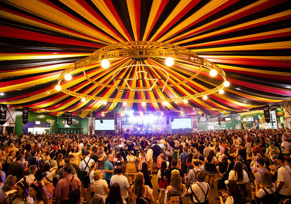 Público em festa sob um teto colorido e iluminado