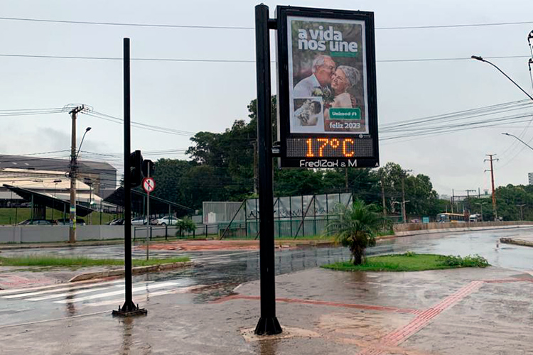 Imagem de um painel fixo em uma esquina de Belo Horizonte, com uma frase sobre a propaganda da Unimed. O dia está nublado e o asfalto um pouco molhado. 