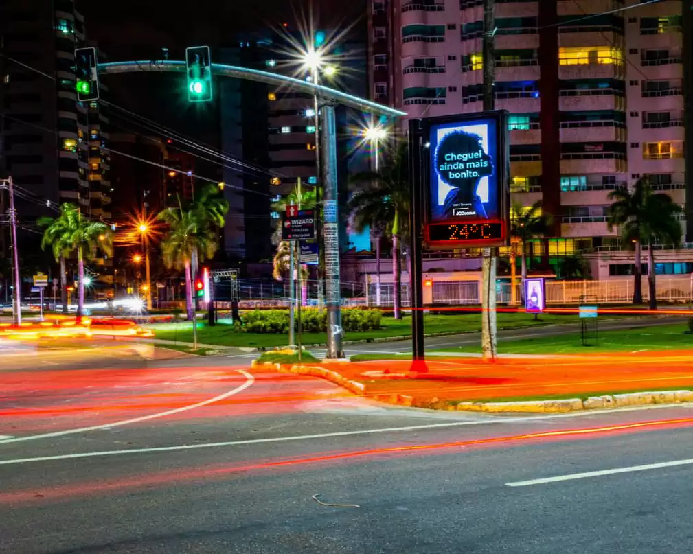 Semáforo e painel digital iluminados à noite na cidade